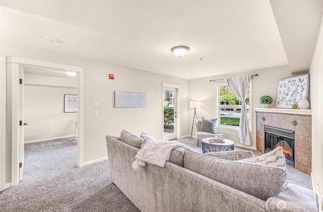 carpeted living room featuring baseboards and a tile fireplace