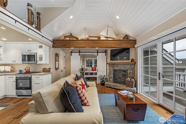 living room featuring recessed lighting, light wood-style floors, vaulted ceiling, and a fireplace