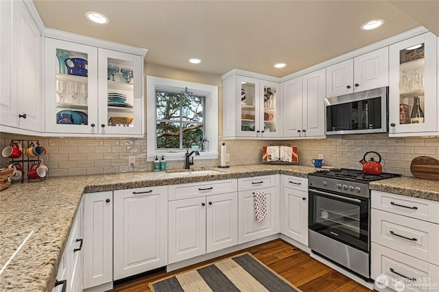 kitchen featuring dark wood-style floors, recessed lighting, white cabinetry, a sink, and appliances with stainless steel finishes