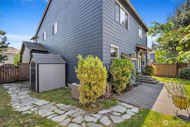 view of home's exterior with fence, a gate, a storage shed, and an outdoor structure