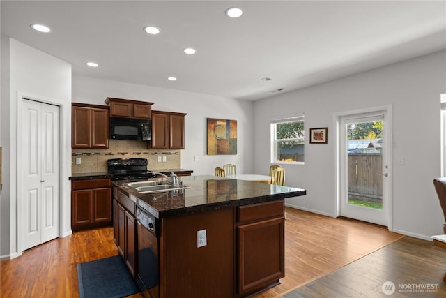 kitchen with black appliances, a sink, light wood-style floors, decorative backsplash, and recessed lighting