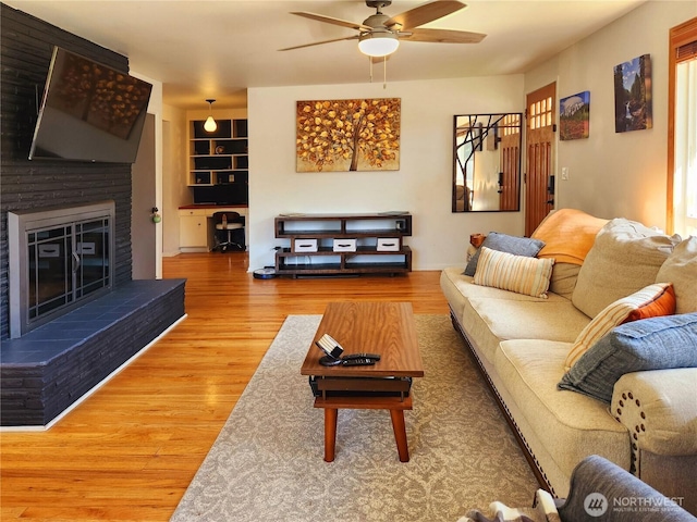 11515 7th Ave NE, Seattle, WA 98125 - living area with a brick fireplace, ceiling fan, built in shelves, and wood finished floors