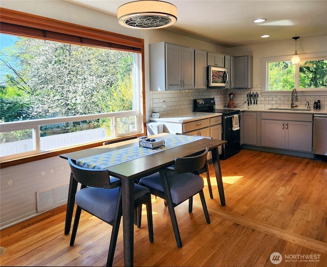 11515 7th Ave NE, Seattle, WA 98125 - kitchen featuring light countertops, gray cabinets, tasteful backsplash, a sink, and stainless steel appliances