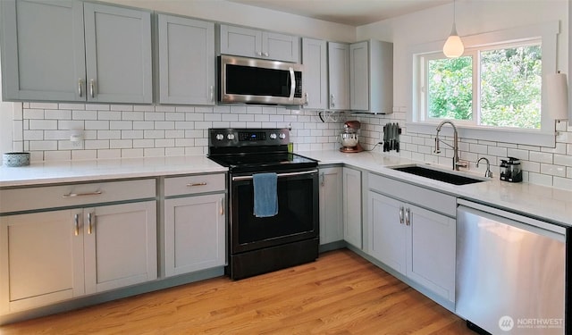 11515 7th Ave NE, Seattle, WA 98125 - kitchen featuring decorative backsplash, light countertops, a sink, gray cabinetry, and stainless steel appliances
