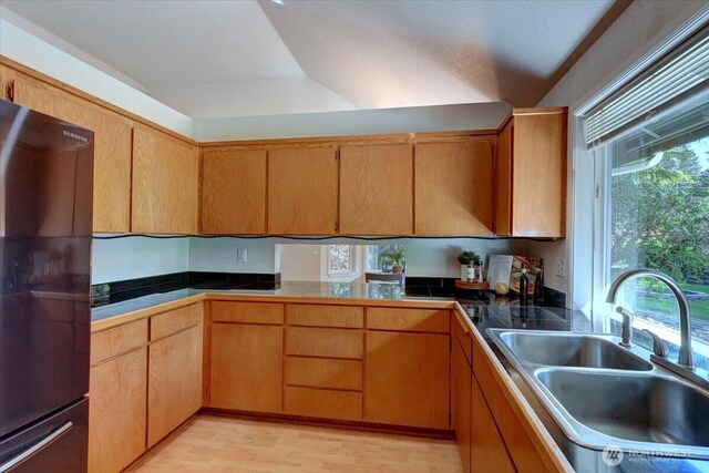 kitchen with freestanding refrigerator, a sink, and light wood-style floors