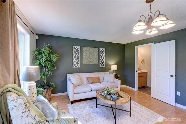 living area with a chandelier, light wood-style floors, and baseboards