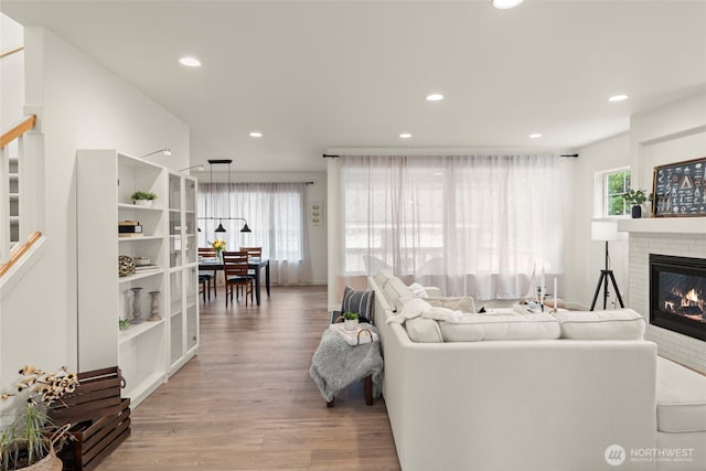 living room with a healthy amount of sunlight, stairway, a fireplace, and wood finished floors