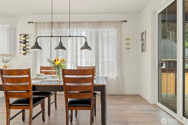 dining space featuring baseboards and light wood-type flooring