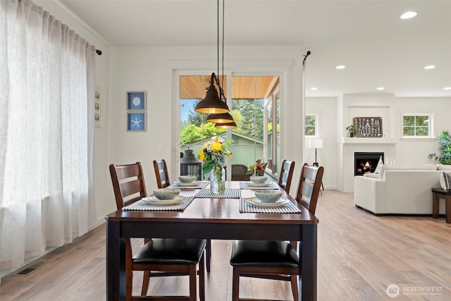dining area featuring light wood-style floors, recessed lighting, visible vents, and a fireplace