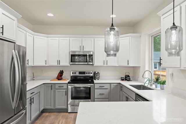 kitchen with a sink, appliances with stainless steel finishes, gray cabinets, and light wood-type flooring