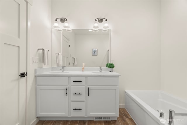 full bathroom with a sink, a bath, double vanity, and wood finished floors