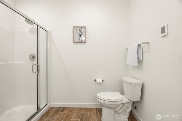bathroom with wood tiled floor, baseboards, a stall shower, and toilet