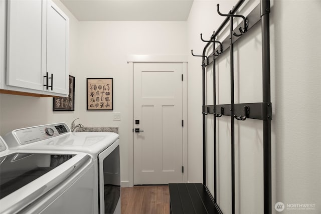 clothes washing area featuring separate washer and dryer, cabinet space, and wood finished floors