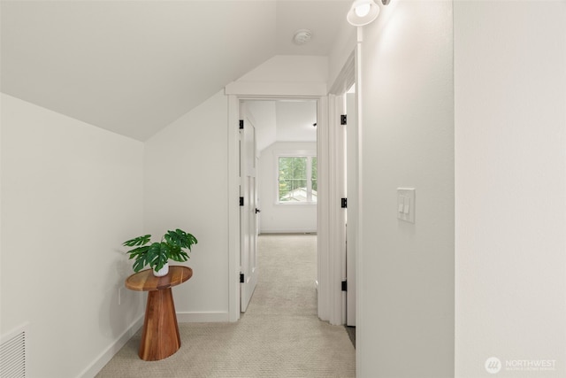 hall with baseboards, visible vents, light colored carpet, and lofted ceiling