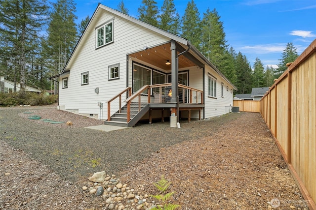 back of property featuring a fenced backyard, a ceiling fan, central AC, and a deck