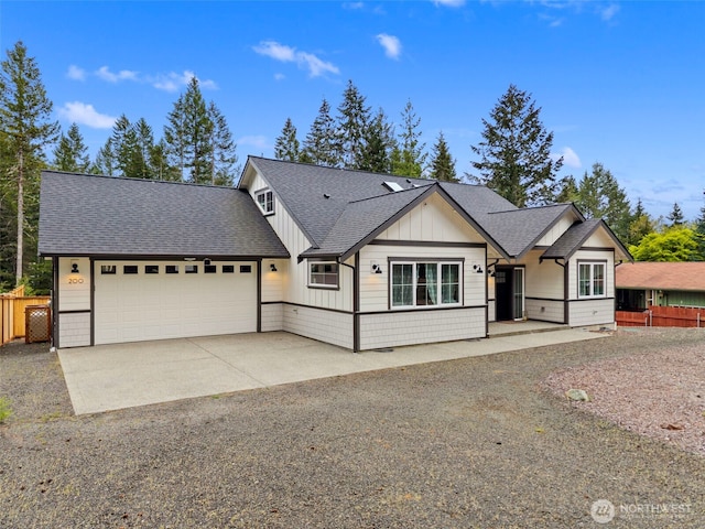 view of front facade with fence, board and batten siding, an attached garage, and driveway