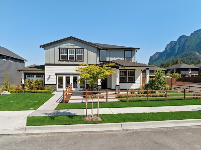 view of front facade featuring french doors, a mountain view, board and batten siding, and a fenced front yard