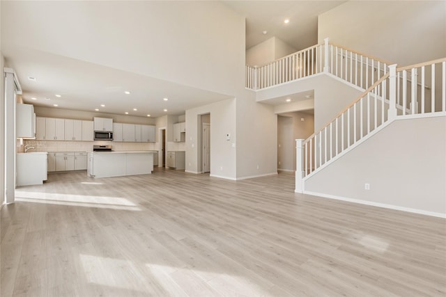 unfurnished living room featuring stairs, recessed lighting, and light wood finished floors