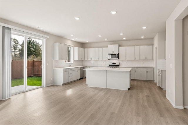 kitchen featuring light wood-style floors, appliances with stainless steel finishes, a kitchen island, and light countertops