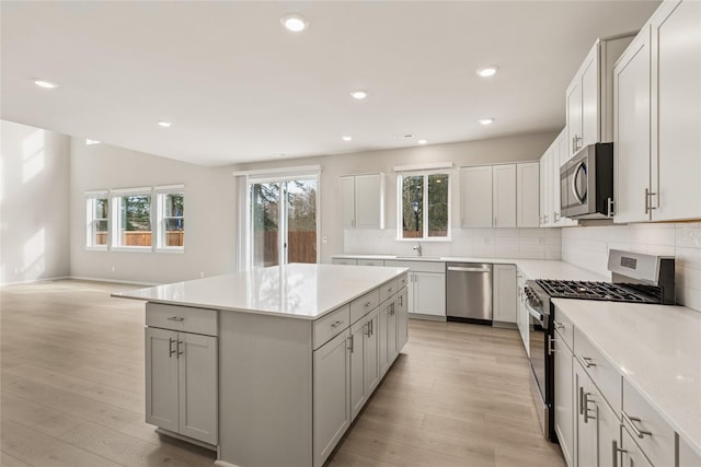 kitchen with a sink, appliances with stainless steel finishes, decorative backsplash, and a healthy amount of sunlight