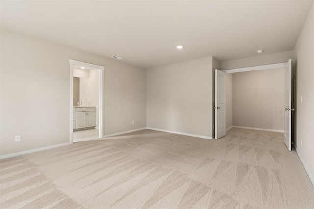 unfurnished bedroom featuring light colored carpet, recessed lighting, baseboards, and ensuite bathroom