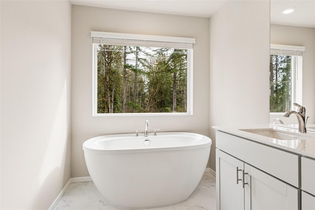 bathroom featuring baseboards, a healthy amount of sunlight, and marble finish floor