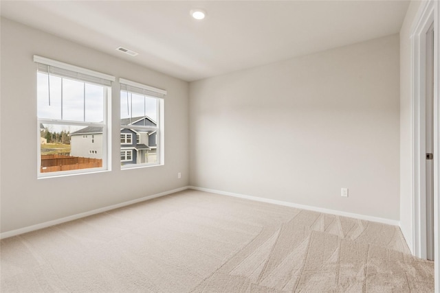 carpeted spare room featuring baseboards and visible vents