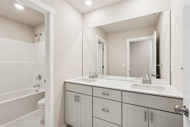 full bath with double vanity, toilet, a sink, and marble finish floor