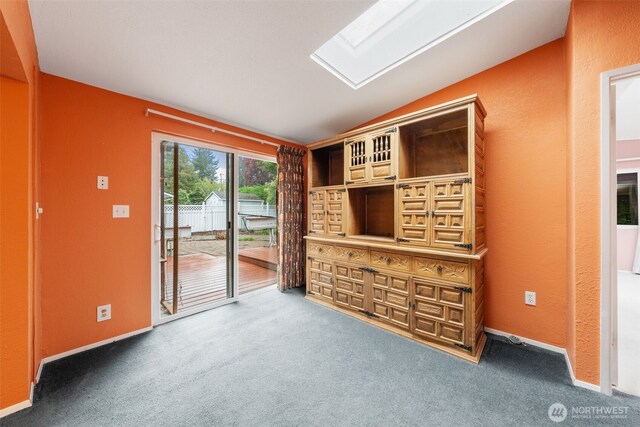 spare room featuring baseboards, carpet, and lofted ceiling with skylight
