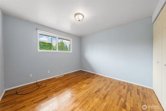 spare room featuring baseboards, light wood-style flooring, and visible vents