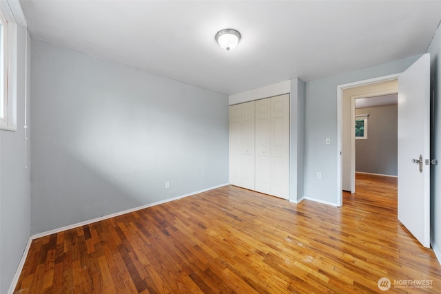 unfurnished bedroom featuring a closet, baseboards, and light wood-type flooring
