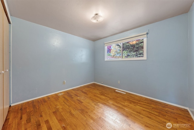 spare room with baseboards, wood finished floors, and visible vents