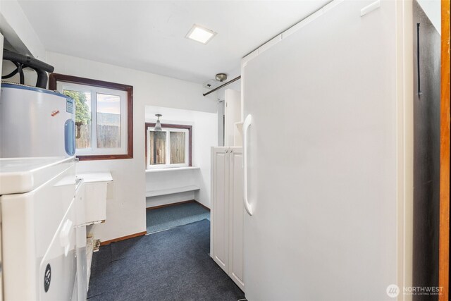 laundry area with dark carpet, washer / dryer, water heater, and baseboards