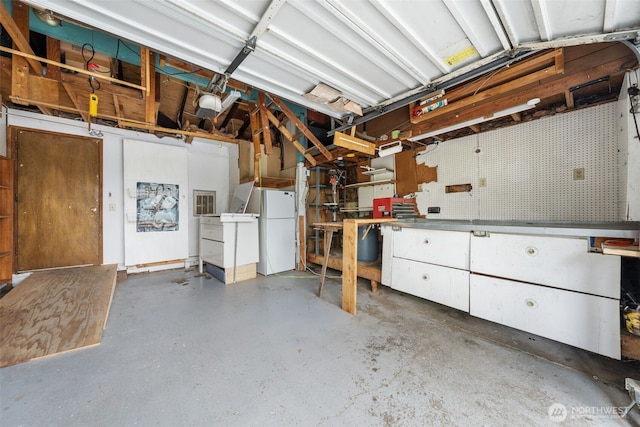 garage featuring freestanding refrigerator and a workshop area