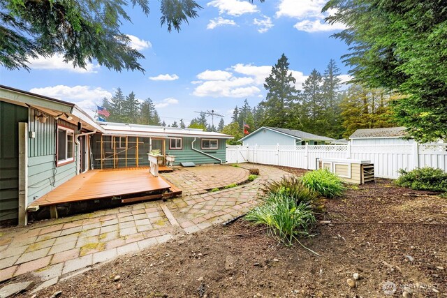 back of house with a sunroom, a patio area, fence, and a deck