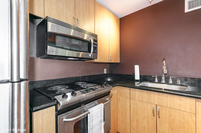 kitchen featuring visible vents, a sink, dark stone countertops, and appliances with stainless steel finishes