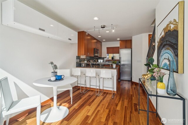kitchen featuring decorative backsplash, a peninsula, wood finished floors, recessed lighting, and appliances with stainless steel finishes