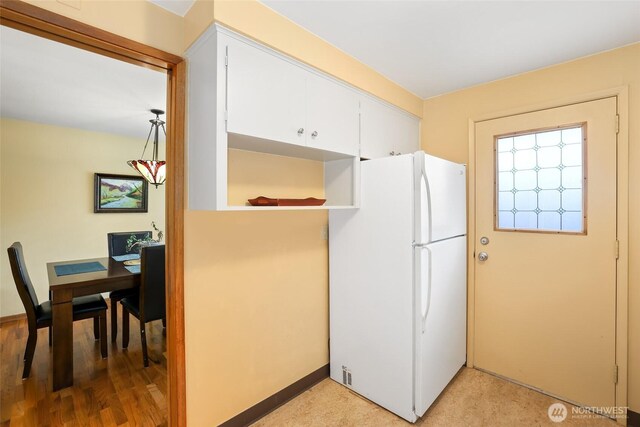 kitchen with freestanding refrigerator, white cabinetry, baseboards, and light wood-style flooring