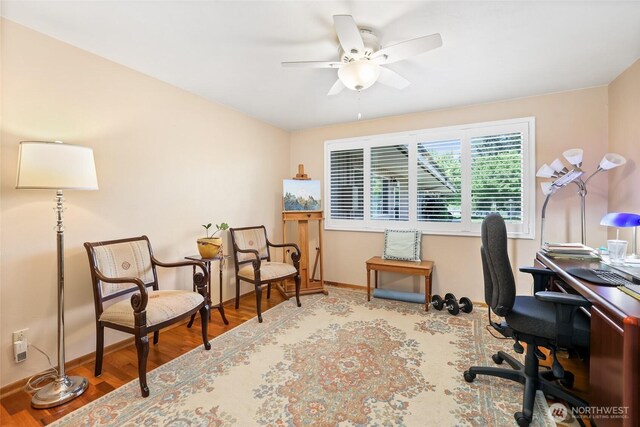 office space featuring baseboards, a ceiling fan, and wood finished floors