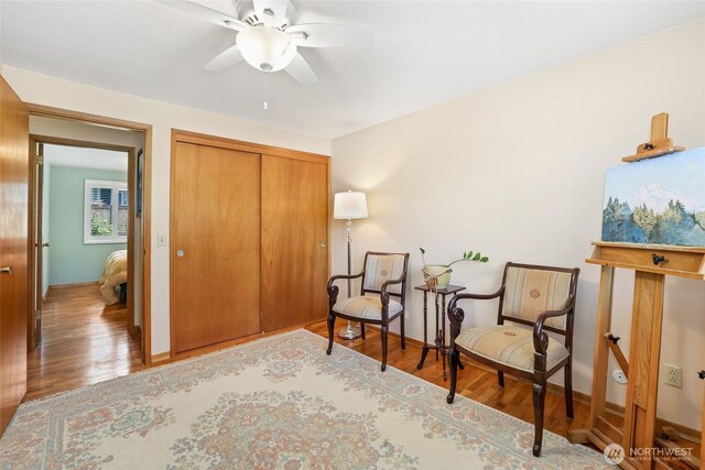 living area with baseboards, ceiling fan, and wood finished floors