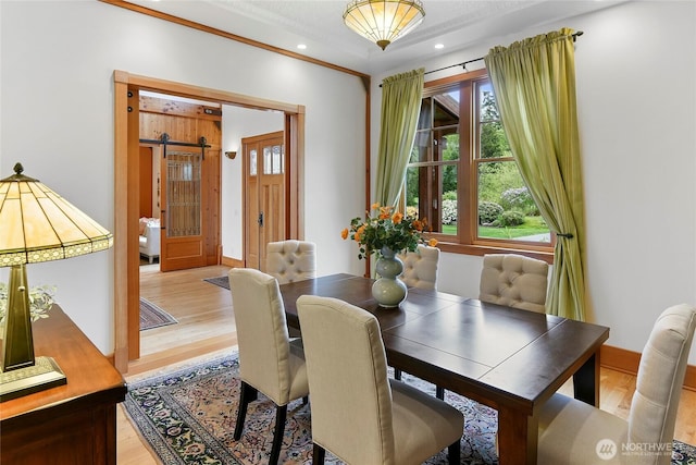 dining room with recessed lighting, baseboards, a barn door, and light wood-style floors