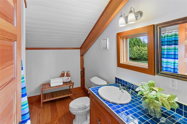full bath with vanity, toilet, baseboards, wood finished floors, and vaulted ceiling