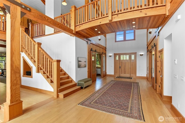entryway with a high ceiling, a barn door, baseboards, wood finished floors, and stairway