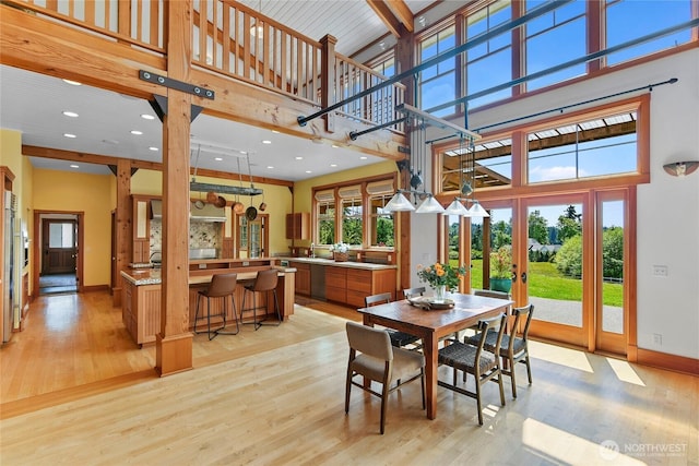 dining area featuring french doors, baseboards, a high ceiling, and light wood-type flooring