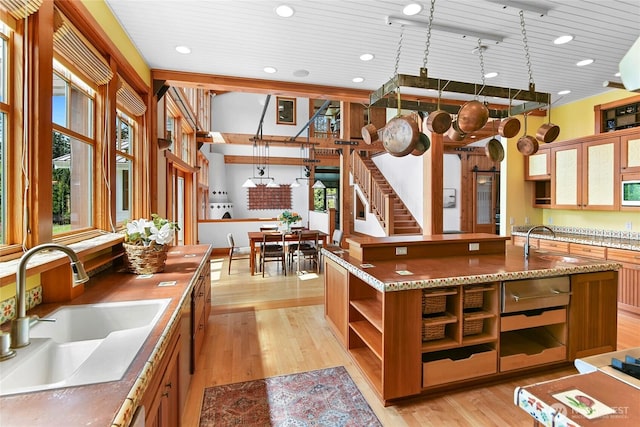 kitchen with open shelves, white microwave, a sink, and light wood-type flooring