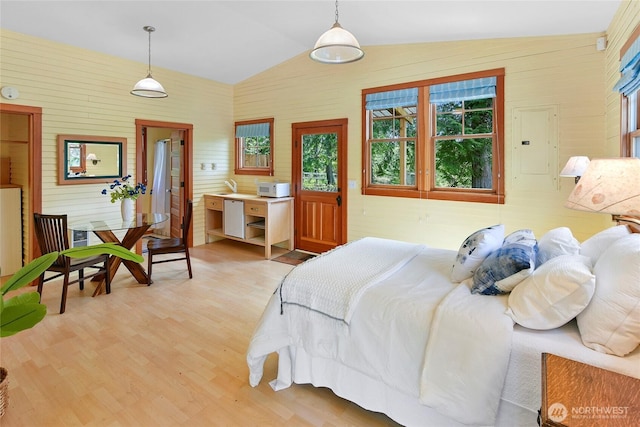 bedroom featuring light wood finished floors, lofted ceiling, electric panel, and wooden walls