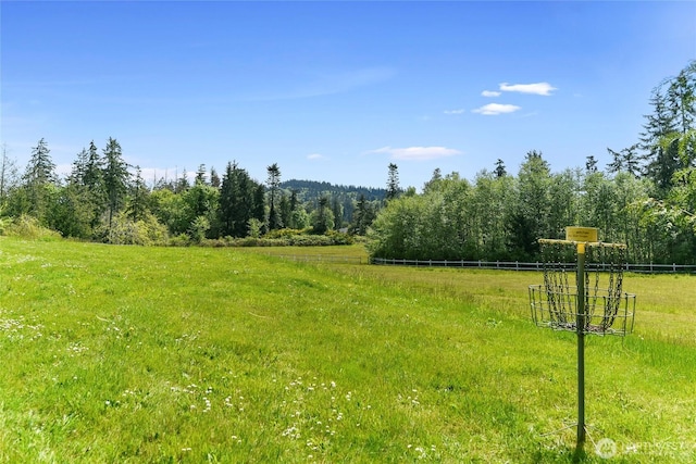 view of yard featuring a forest view and fence
