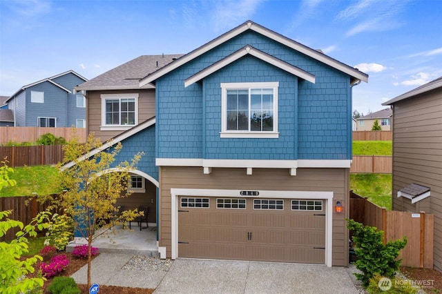 view of front of house featuring an attached garage, fence, and concrete driveway