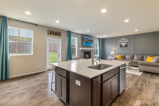 kitchen with visible vents, a sink, a warm lit fireplace, and open floor plan