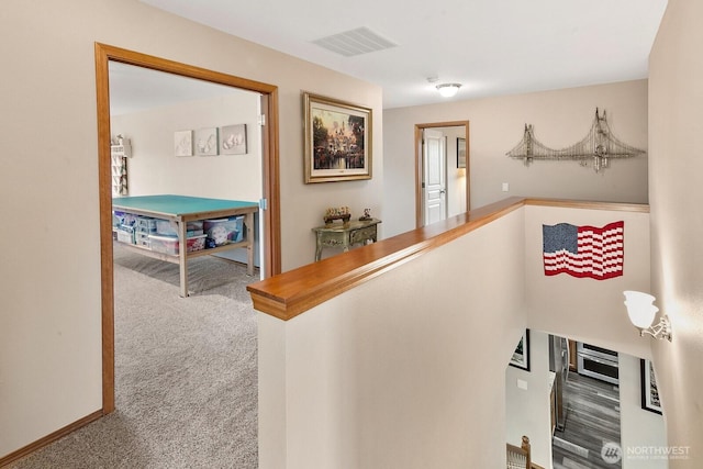 hallway with carpet floors, an upstairs landing, and visible vents